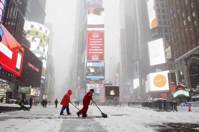 Workers shovel snow during a snowstorm at Times Square in the Manhattan borough of New York January 23, 2016. REUTERS/Shannon Stapleton